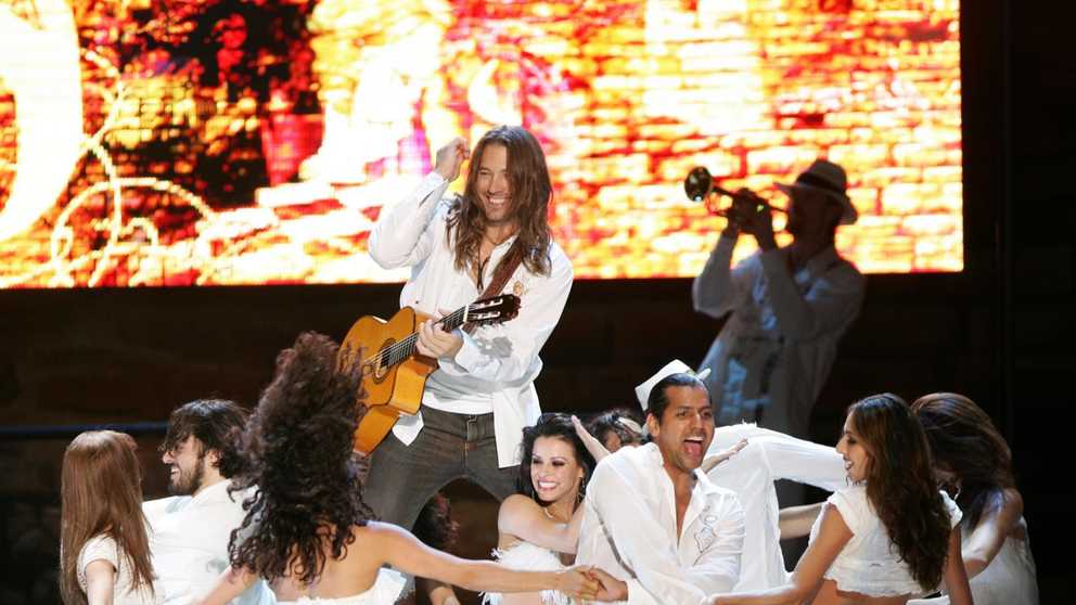 Benise - 25 Years of Passion! Benise plays guitar while dancers swirl around him. 
