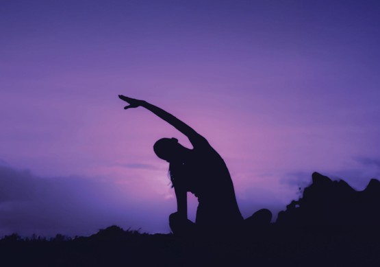 Woman doing yoga outdoors at sunrise
