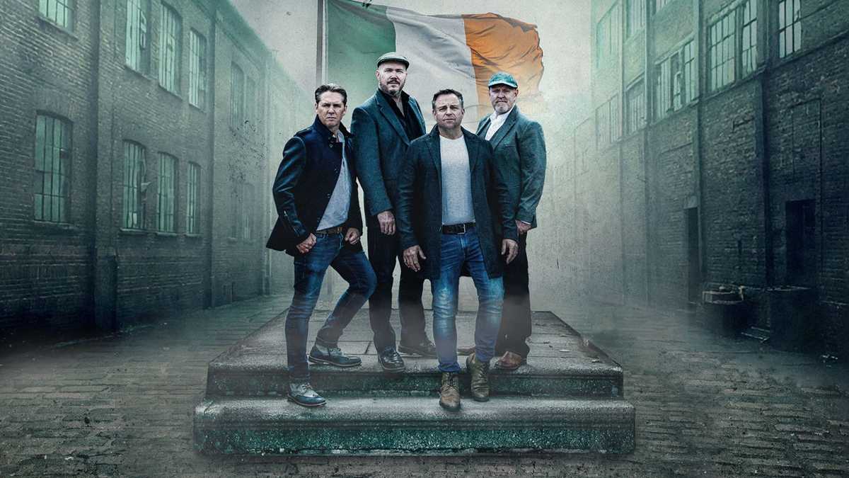 Members of the High KIngs standing in front of the flag of Ireland