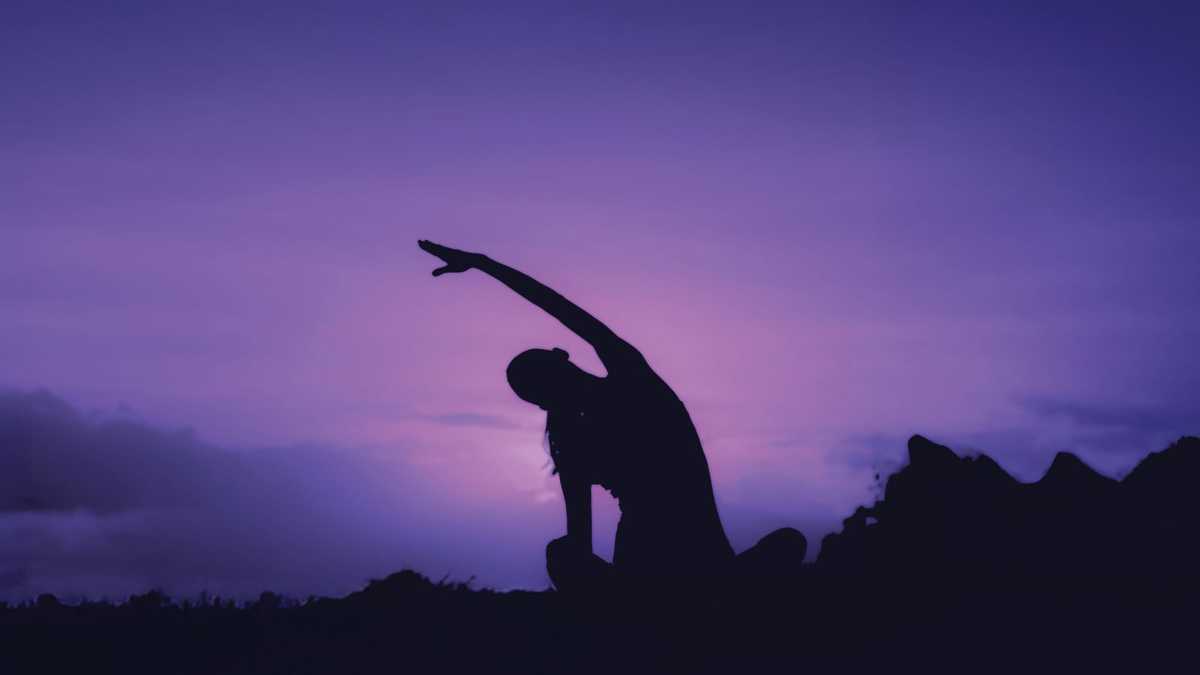 Woman doing yoga outdoors at sunrise
